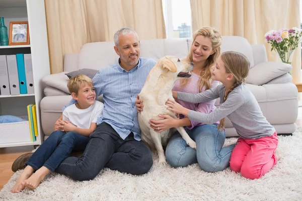 Pais e crianças no tapete com labrador — Fotografia de Stock