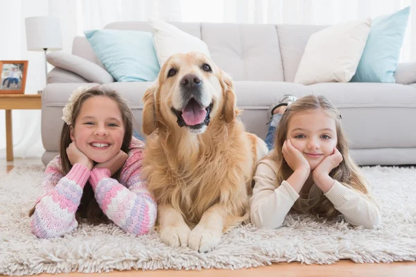 Sisters lying on rug with retriever — Stock Photo, Image