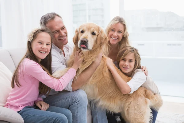 Family petting golden retriever on the couch — Stock Photo, Image