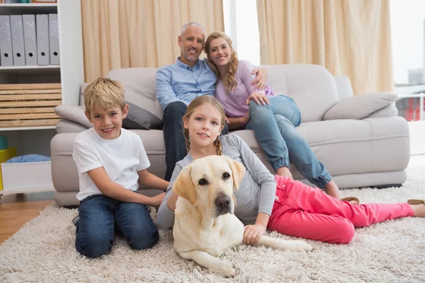 Pais e filhos no sofá com labrador — Fotografia de Stock