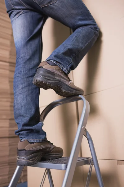 Worker on ladder in warehouse — Stock Photo, Image