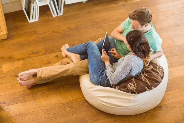 Couple using tablet pc on beanbag — Stock Photo, Image