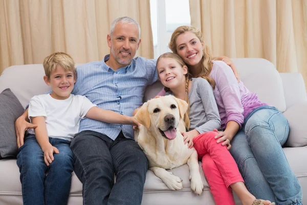 Pais e filhos no sofá com labrador — Fotografia de Stock