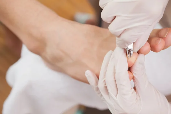 Fußpflegerin schneidet Kunden Zehennägel — Stockfoto