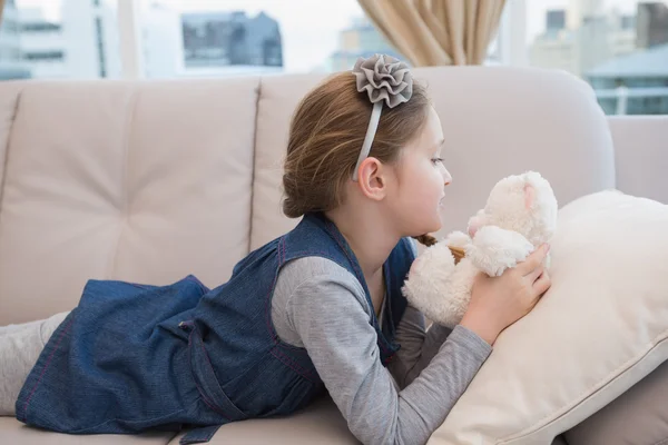 Tjejen ligger på soffan med teddy — Stockfoto