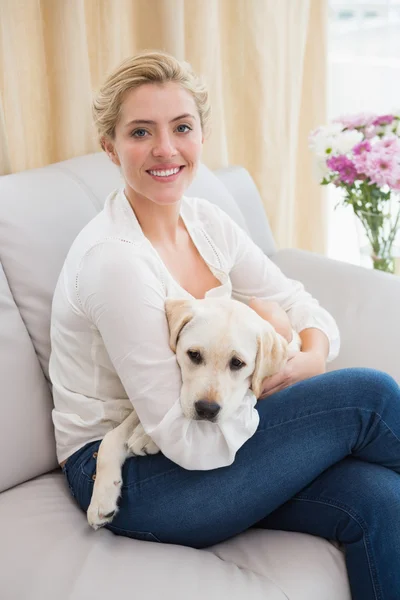 Woman cuddling with puppy on sofa — Stock Photo, Image