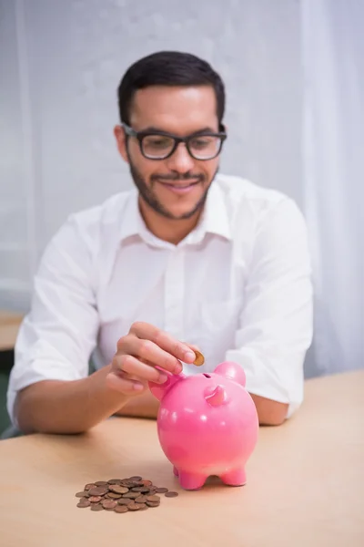 Geschäftsmann steckt Münzen in Sparschwein — Stockfoto