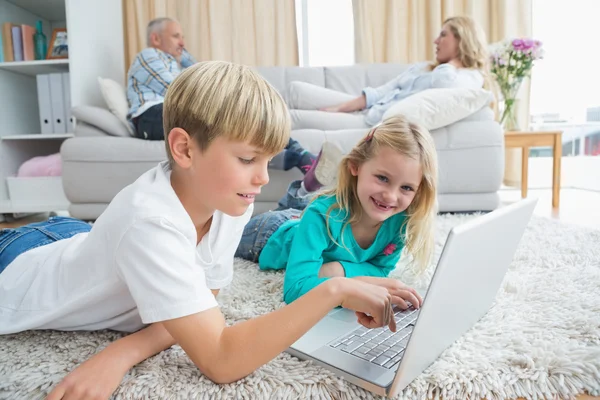 Broers en zussen met behulp van laptop op verdieping — Stockfoto