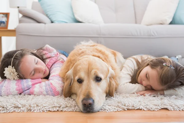 Zusters dutten op tapijt met retriever — Stockfoto