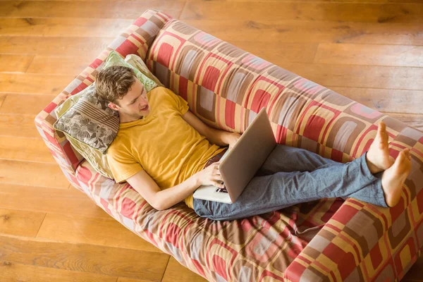 Człowiek za pomocą laptopa na kanapie — Zdjęcie stockowe
