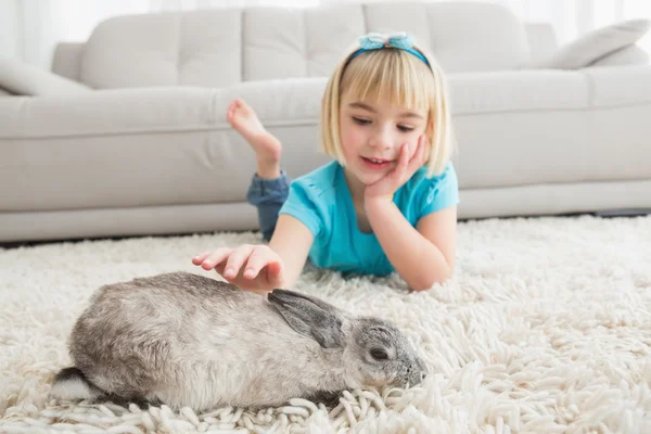 Dívka ležela na koberci hladil králík — Stock fotografie