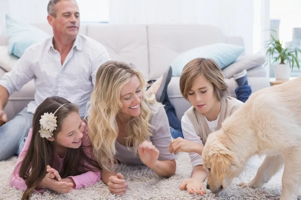 Familie met gele labrador op tapijt — Stockfoto