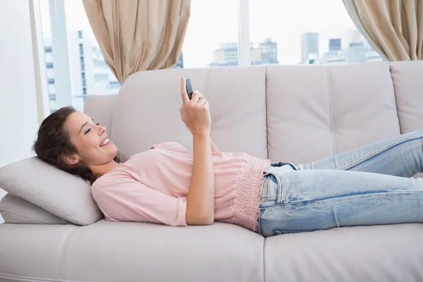 Mulher usando smartphone no sofá — Fotografia de Stock