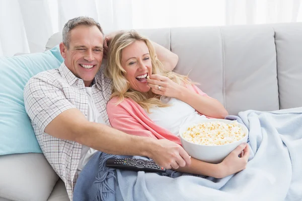 Пара ест попкорн во время просмотра телевизора — стоковое фото