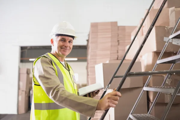 Werknemer met dagboek in magazijn — Stockfoto