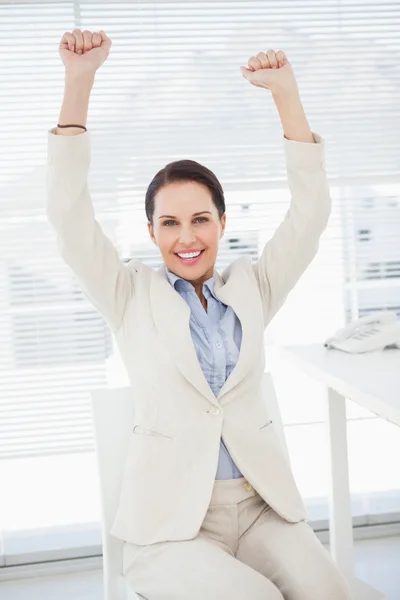 Empresária sentada e celebrando no trabalho — Fotografia de Stock