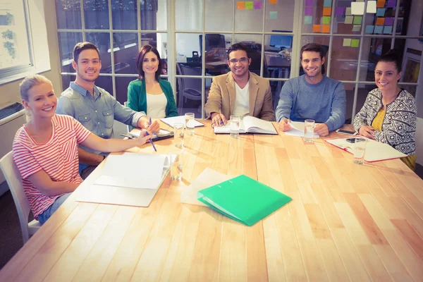 Lächelnde Geschäftsleute blicken während eines Meetings in die Kamera — Stockfoto