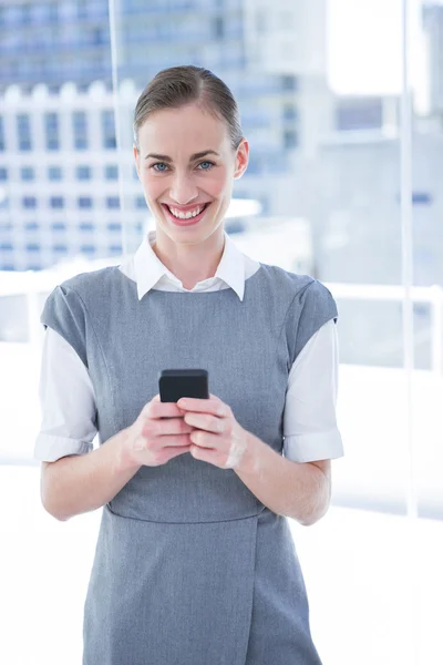 Улыбающаяся деловая женщина смс с мобильного телефона — стоковое фото