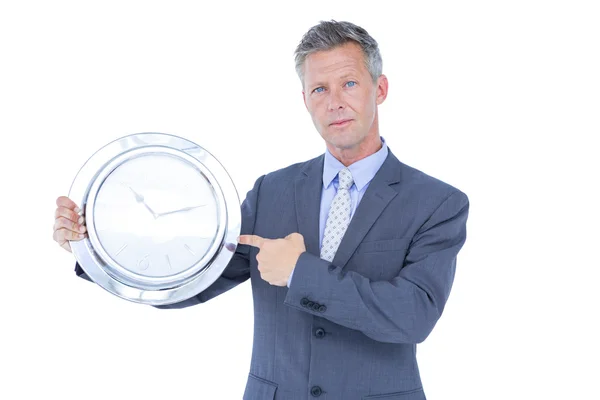 Homme d'affaires tenant et montrant une horloge — Photo