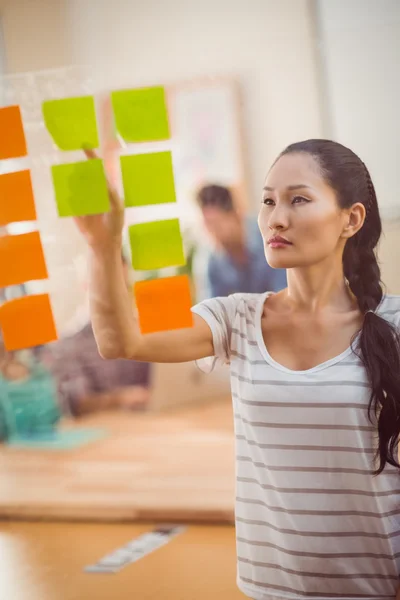 Wijzende zakenvrouw post geconcentreerd zijn op de muur — Stockfoto