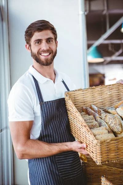 Portrait of happy worker holding basket of bread — Stock Photo, Image