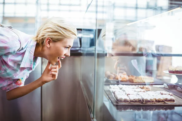 Mujer bonita desconcertada mirando tortas de la taza — Foto de Stock