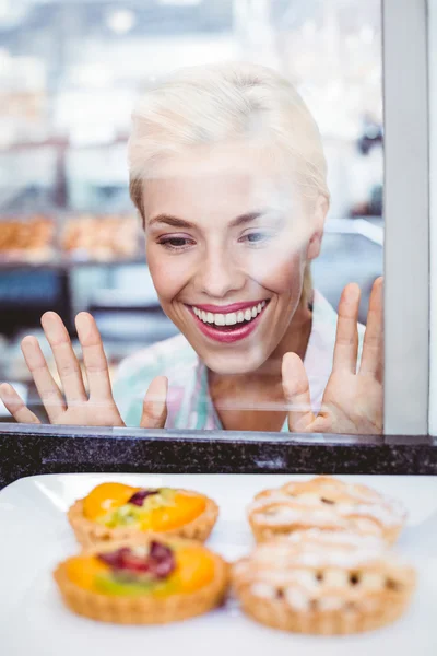 Sconcertato bella donna guardando una torta di frutta attraverso il vetro — Foto Stock