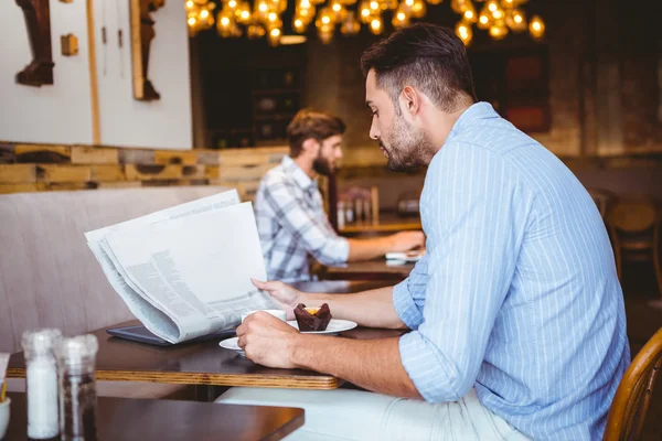 Businessman reading a newspaper while eating — Stock Photo, Image