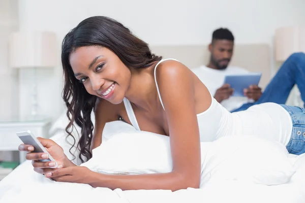 Casal relaxado usando a tecnologia na cama — Fotografia de Stock
