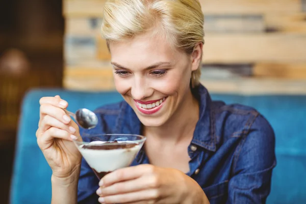 Улыбающаяся блондинка ест сливочный шоколад — стоковое фото