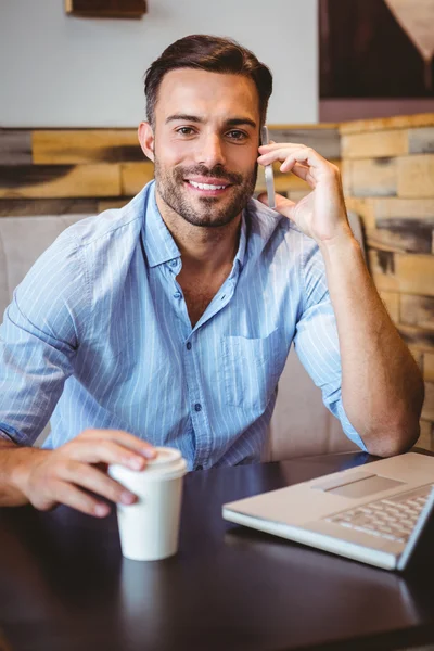 Sonriente hombre de negocios en el teléfono con el ordenador portátil al lado — Foto de Stock
