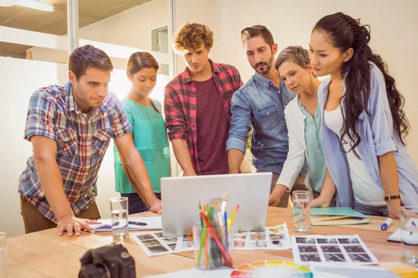 Glückliches kreatives Geschäftsteam mit Laptop in Besprechung — Stockfoto