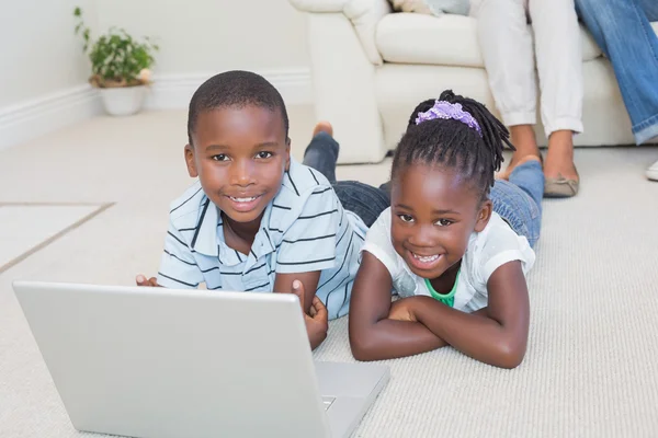 Gelukkig broers en zussen liggend op de vloer met behulp van laptop — Stockfoto