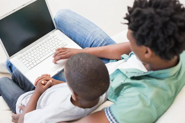 Pai e filho usando laptop no sofá — Fotografia de Stock