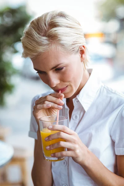 Mujer joven tomando un vaso de jugo de naranja — Foto de Stock