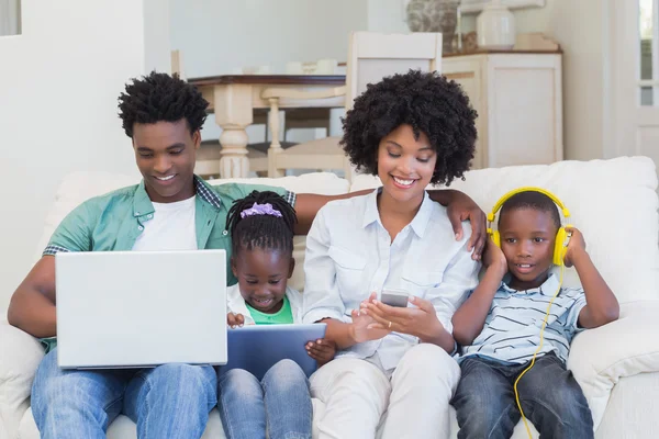 Familia feliz usando tecnologías en el sofá — Foto de Stock