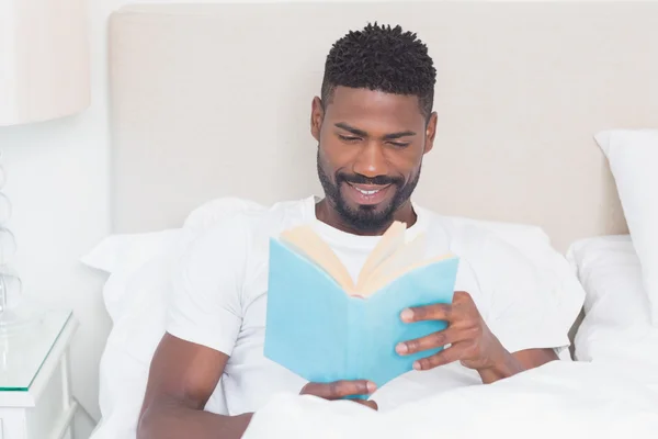 Όμορφος άντρας ανάγνωση στο κρεβάτι — Φωτογραφία Αρχείου