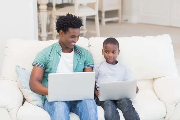 Pai e filho usando laptops no sofá — Fotografia de Stock