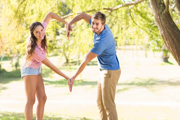 Bonito casal fazendo forma de coração com as mãos — Fotografia de Stock