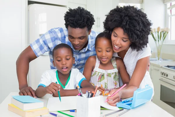 Pais felizes ajudando crianças com lição de casa — Fotografia de Stock