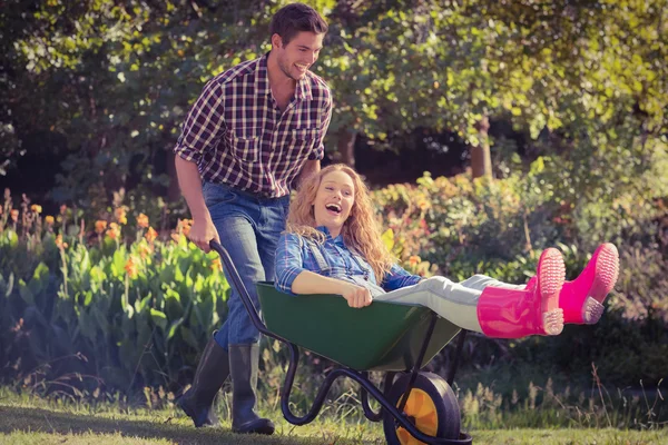 Man pushing his girlfriend in wheelbarrow — Stock Photo, Image