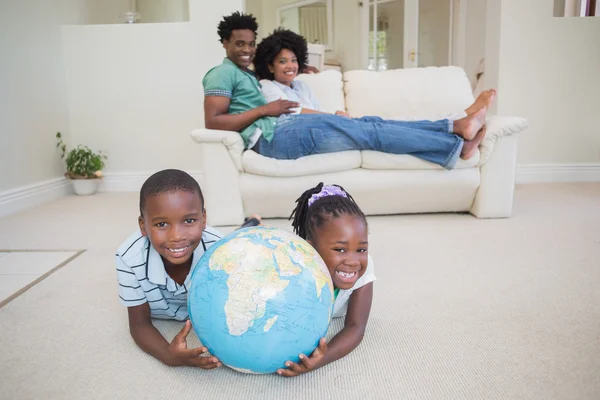 Glückliche Geschwister auf dem Boden liegend mit Globus — Stockfoto