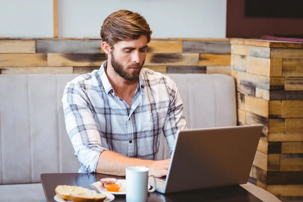 Étudiant souriant utilisant un ordinateur portable dans un café — Photo