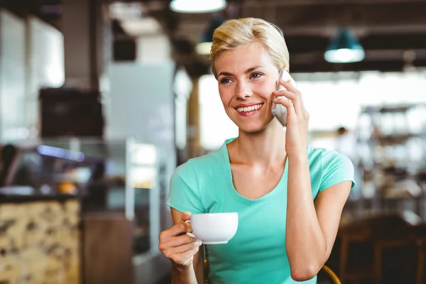 Mulher loira bonita usando seu smartphone com uma xícara de café — Fotografia de Stock