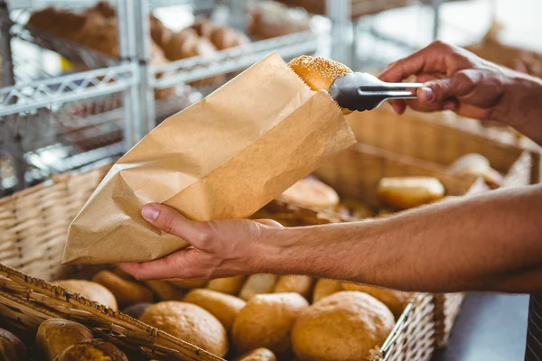 Garçom sorridente tomando pão com pinças — Fotografia de Stock