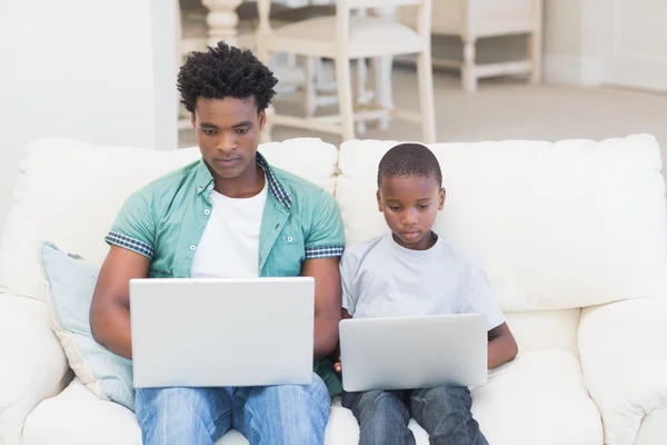 Pai e filho usando laptops no sofá — Fotografia de Stock