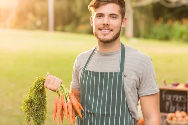 Knappe landbouwer bedrijf wortelen — Stockfoto