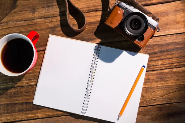 En penna på anteckningar bredvid koppen kaffe och kamera — Stockfoto