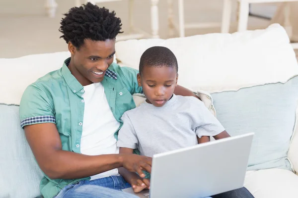 Pai e filho usando laptop no sofá — Fotografia de Stock