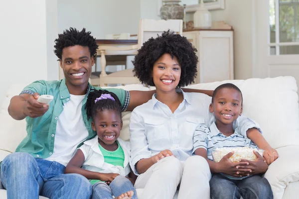 Felice famiglia guardando la televisione mangiare popcorn — Foto Stock